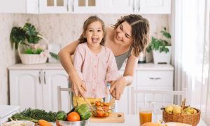Glückliches Kind mit Frau kochen